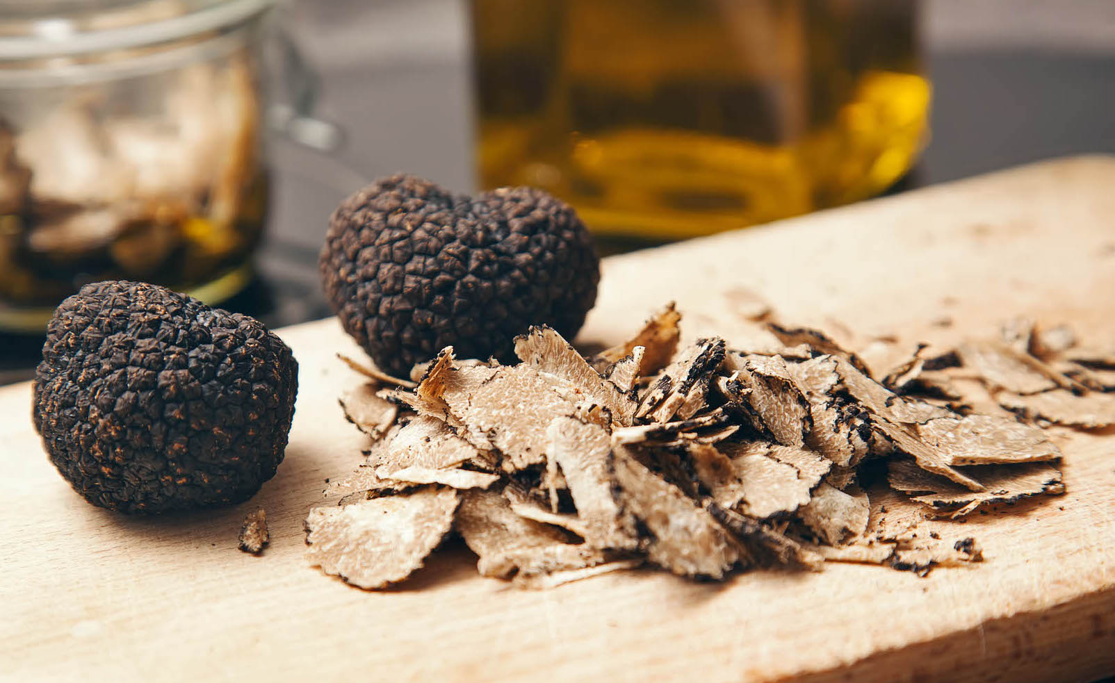 Whole and shaved black truffled on a wooden cutting board. Gourmet Spice Company, Wholesale Food Distributor.