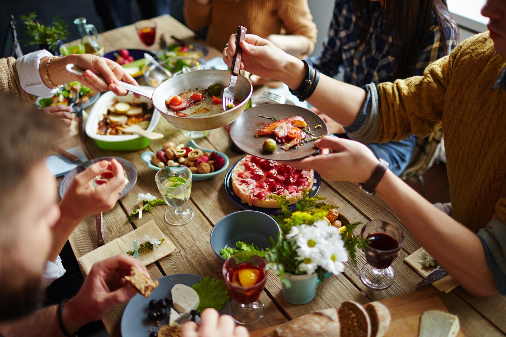 Friends at dinner party plating up with colorful dishes, foods and drinks. Gourmet Spice Company, Wholesale Food Distributor.